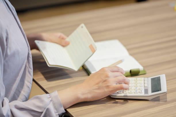 istock Hand of woman hitting calculator while looking at bankbook 1173752337