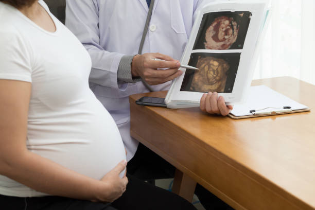 医師は4d超音波画像の結果を保持し、妊娠中の女性に話します。妊娠中の概念 - two dimensional shape ストックフォトと画像
