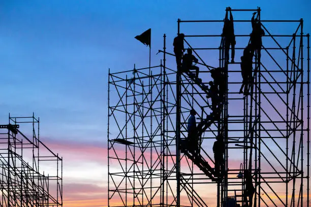 The workers are climbing the silhouette of scaffolding in the high altitude, horizontal and vertical scaffolding formed a myriad of grid, industrial and modern urban construction background