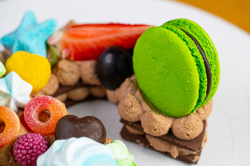 Close-up on green macaroon, candies and fruit decorating artisanal cake