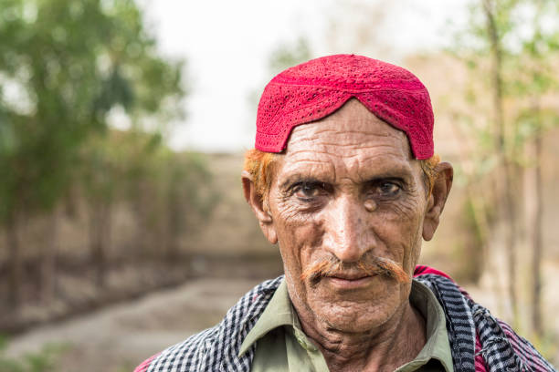 an old staring poor asian farmer wearing Pakistani traditional clothes