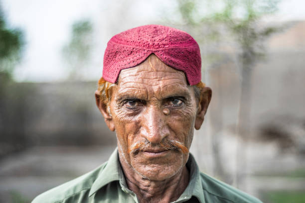 an old staring poor asian farmer wearing Pakistani traditional clothes