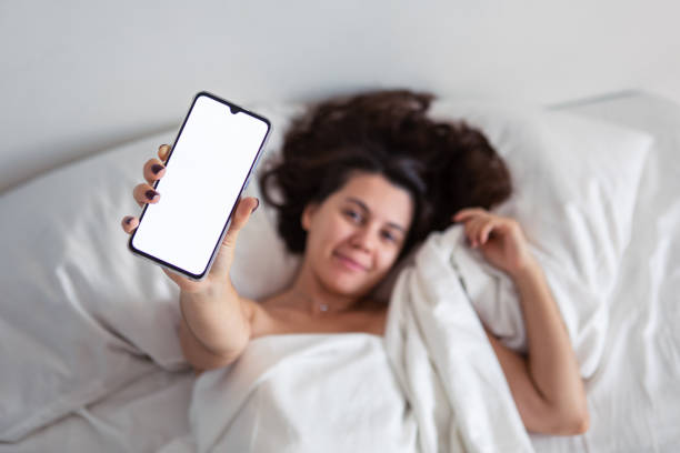 istock woman laying in bed showing phone with white screen 1173771120