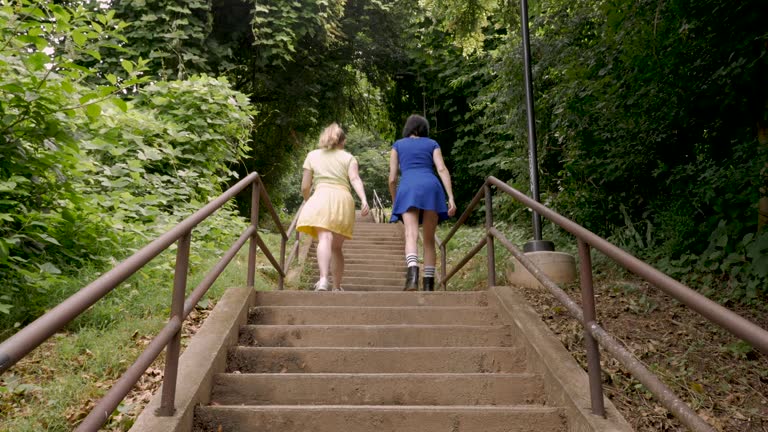 Two young women walking up stairs together surrounded by trees