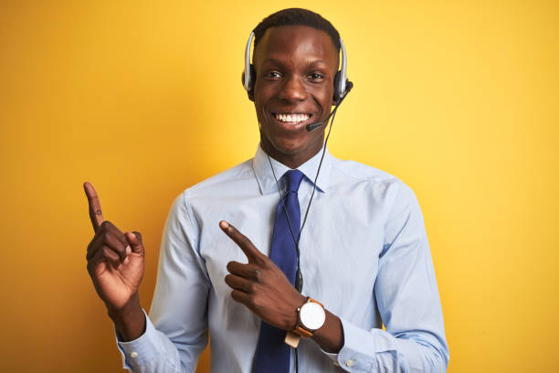 istock African american operator man working using headset over isolated yellow background smiling and looking at the camera pointing with two hands and fingers to the side. 1173776969