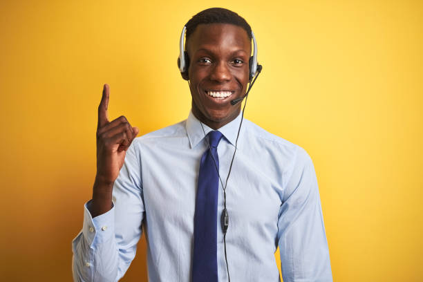istock African american operator man working using headset over isolated yellow background pointing finger up with successful idea. Exited and happy. Number one. 1173777027