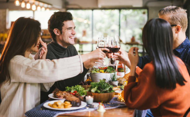 cena con amigos. grupo de jóvenes disfrutando de la cena juntos. dining wine cheers party concepto de acción de gracias - holiday season turkey food fotografías e imágenes de stock