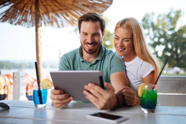 istock Smiling young couple using digital tablet in a beach bar 1173787025