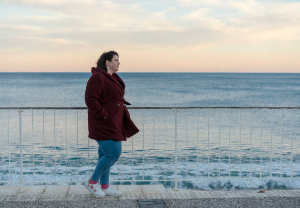 istock Young fat woman standing alone on the beach 1173791626