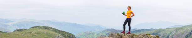istock Woman drinking water on mountain top overlooking wilderness panorama 1173801862