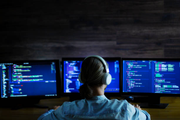 Software developer, freelancer working with program code Software developer freelancer man male with white headphones working with program code: C++, Java, Javascript on wide displays at night. Develops new web, desktop, mobile application or framework. broadcast programming stock pictures, royalty-free photos & images
