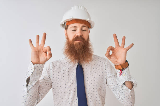 istock Young redhead irish architect man wearing security helmet over isolated white background relax and smiling with eyes closed doing meditation gesture with fingers. Yoga concept. 1173811340