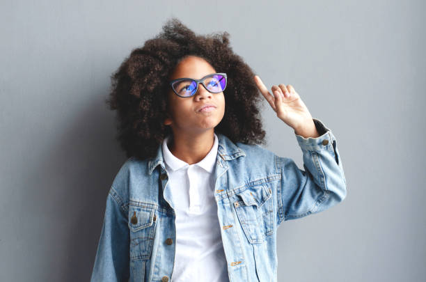 istock A dark-skinned girl thought for a moment, leaning a pencil on her lips. 1173811465
