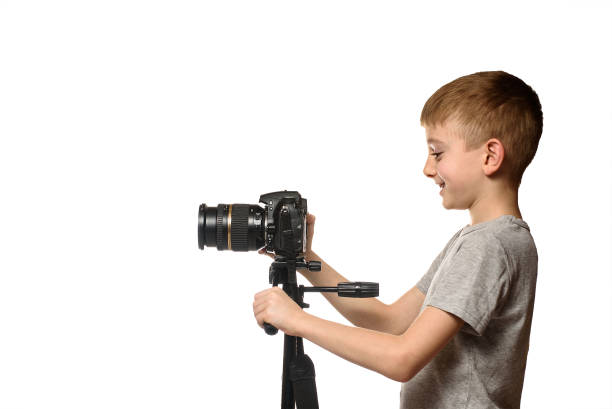 istock Schoolboy shoots video on DSLR camera. Side view. White background, isolate 1173812686