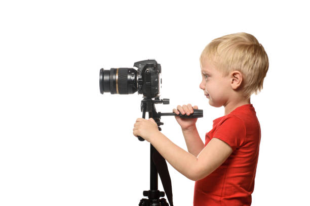 istock Blond boy shoots video on DSLR camera. Side view. White background, isolate 1173812705