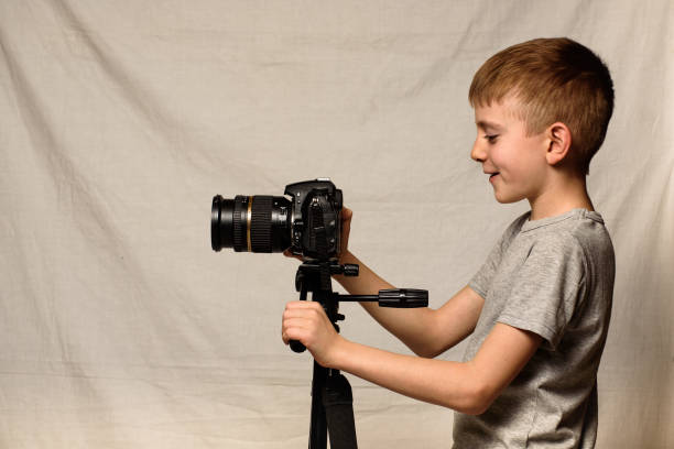 istock Schoolboy shoots video on DSLR camera. Side view. Home studio 1173812715
