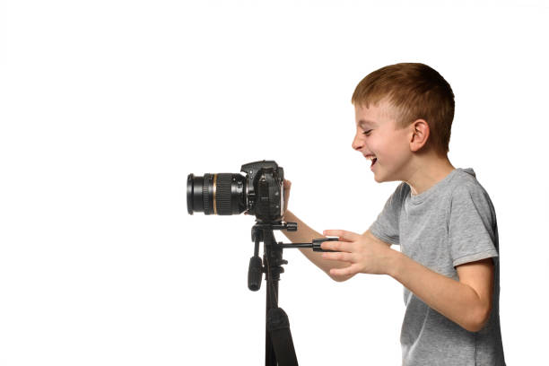 istock Laughing schoolboy shoots video on DSLR camera. Side view. White background, isolate 1173812742