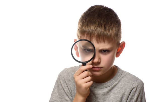 istock Serious boy with a magnifying glass in his hands. Little explorer. White background 1173812790