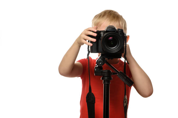 istock Blond boy takes pictures with a SLR camera. Front view. White background, isolate 1173812879
