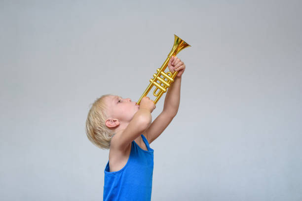 istock Little cute blond boy playing toy trumpet on light background 1173812913