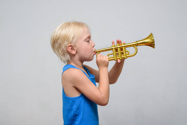 istock Little cute blond boy playing toy trumpet on light background 1173812920