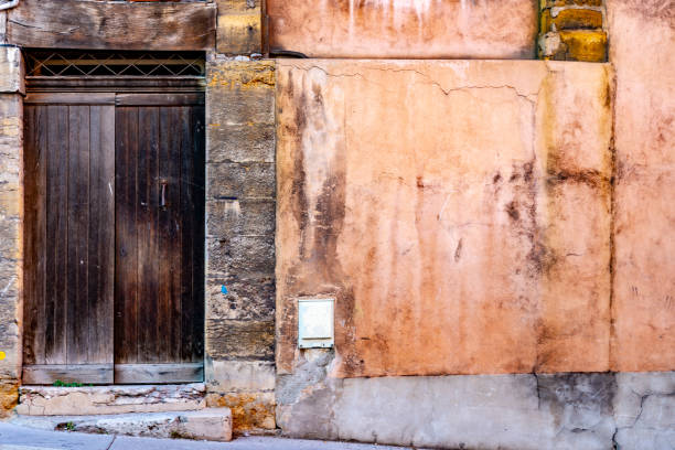 Dilapidated building exterior in Lyon with peeling paint and worn concrete surround.