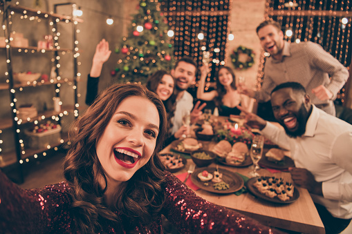 Close up photo of cheerful fellows in formal wear sit around table enjoy, christmas party x-mas holidays making selfie in house full of noel decoration