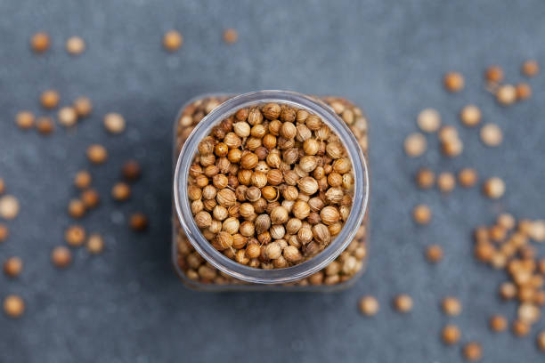 Coriander seeds in a jar on grey stone background. Top view. Copy space. stock photo