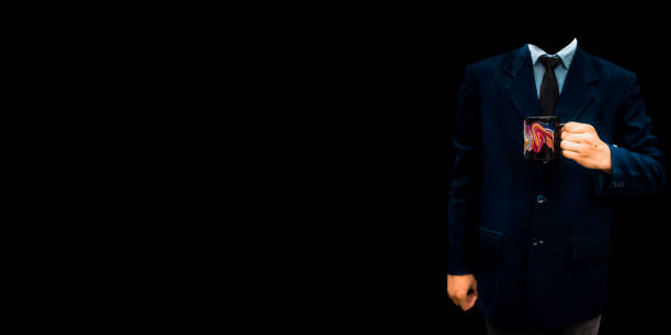 An unrecognizable office employee wearing a blue colored suit and posing with a cup of coffee in his hands isolated on a black colored background.
