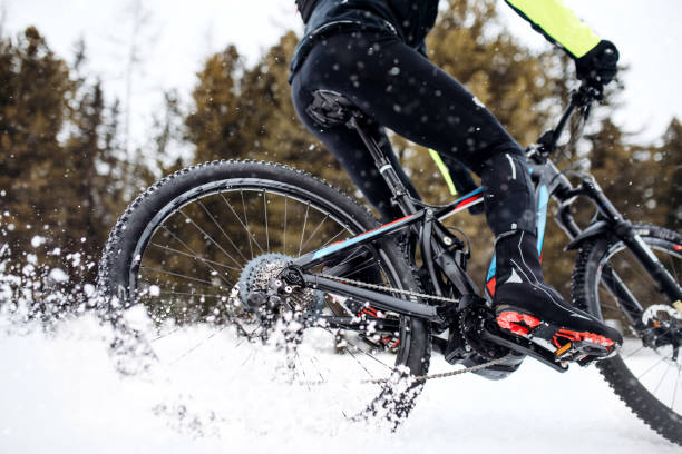 Midsection of mountain biker riding in snow outdoors in winter.