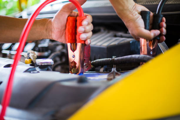 istock selective focus hands do charging yellow car battery with electricity through cables from from other car, 1173831096