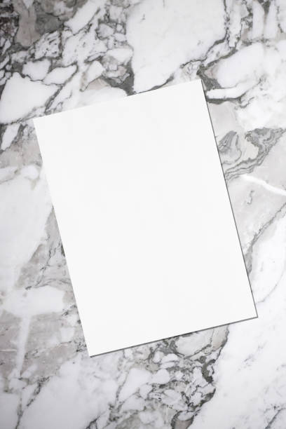 istock Empty white vertical rectangle poster or business card mockup with soft shadow lying diagonally on grey marble background 1173832422