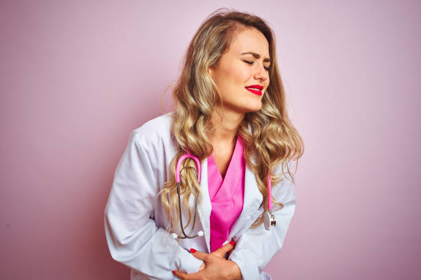 istock Young beautiful doctor woman using stethoscope over pink isolated background with hand on stomach because nausea, painful disease feeling unwell. Ache concept. 1173835577
