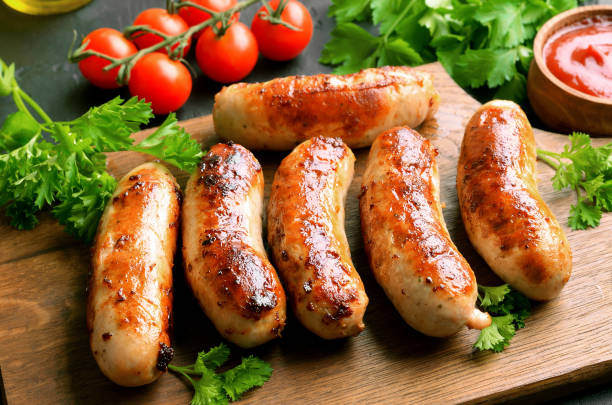 istock Fried sausages on a cutting board, sause and cherry tomatoes 1173840221
