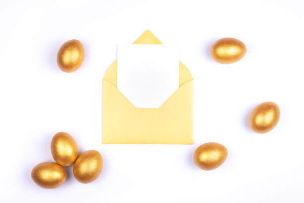 istock Golden colored Easter eggs, blank card in opened golden envelope on white background. Place for text. 1173842301