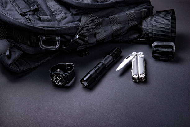 Tactical gear and black backpack on dark background.