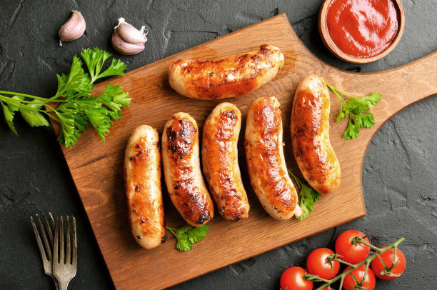istock Roasted sausages on a cutting board, sause and cherry tomatoes 1173842992
