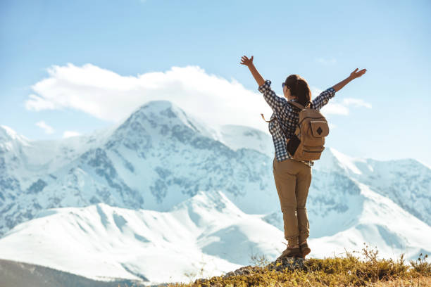 istock Happy lady hiker stands with raised arms against mountains 1173843892