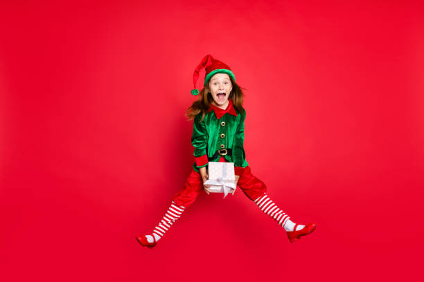 Full length body size profile side view of nice attractive cheerful positive, overjoyed glad funny small little pre-teen elf holding in hands white box isolated over bright vivid shine red background vista lateral del perfil del tamaño del cuerpo de longitud completa de agradable atractivo positivo alegre alegre alegre alegre alegre poco divertido pequeño elfo preadolescente sosteniendo en las manos caja blanca aislada sobre brillante brillo brillant