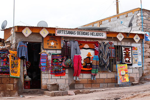 People walking outside 4 Way Shebeen at Katutura Township near Windhoek in Khomas Region, Namibia, with graffiti and posters in the background.