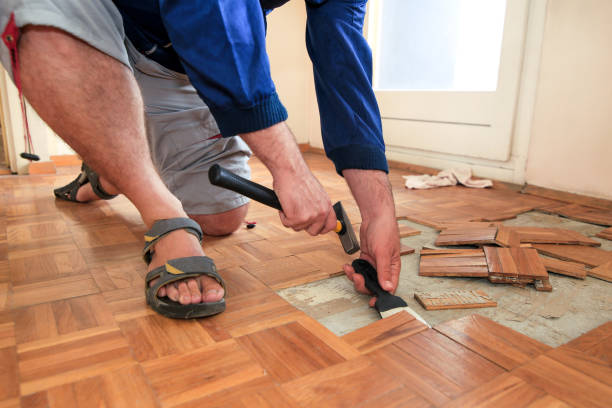 istock Construction worker and constructor is working on renovation of apartment. Handyman is removing old wooden parquet flooring using yellow hammer and scraping tool. Builder dismantles parquet floor. 1173844847