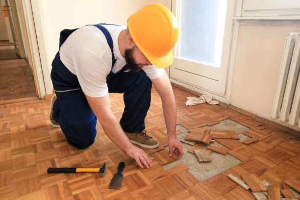 istock Construction worker and constructor is working on renovation of apartment. Handyman is removing old wooden parquet flooring using yellow hammer and scraping tool. Builder dismantles parquet floor. 1173845084
