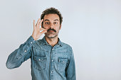 Funny portrait of brown, smiling, handsome man touching his mustache. Jeans shirt.