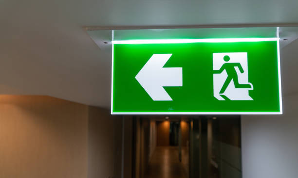 istock Green fire escape sign hang on the ceiling in the office. 1173847444