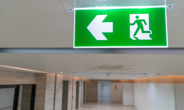 istock Green fire escape sign hang on the ceiling in the office. 1173847460