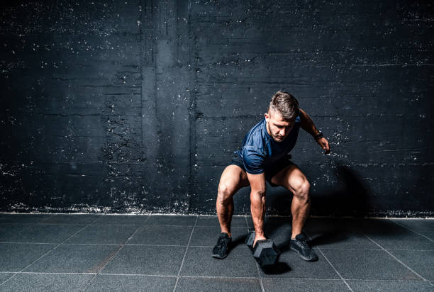istock Young strong fit muscular sweaty man with big muscles strength cross workout training with dumbbells weights in the gym dark image with shadows real people 1173847762