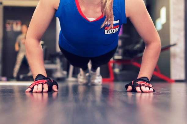 das mädchen - brünette in tarnung an den händen gedrückt, hände in schwarzen handschuhen ohne finger nah auf dem boden mitainen. - fitnesscenter stock-fotos und bilder