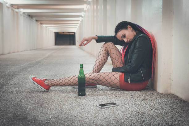 istock Young depressed girl drinking alcohol and smoking in the underpass while waiting for important phone call. toper, drunkard, drunk, drinker. woman looks at the smartphone screen with a sad look. 1173850816