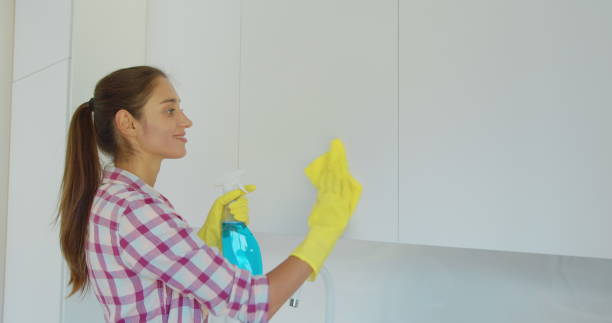 istock Woman's hand in a yellow rubber glove cleans the shiny surface of a modern plastic kitchen Cabinet with a cloth. The concept of spring cleaning and home work. 1173853048