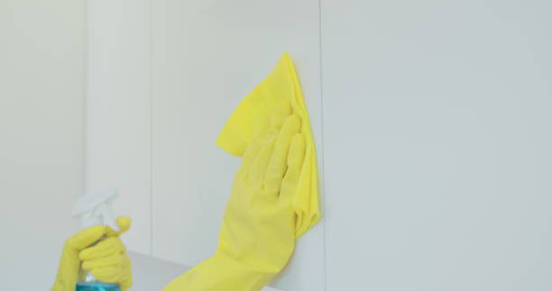 istock Woman's hand in a yellow rubber glove cleans the shiny surface of a modern plastic kitchen Cabinet with a cloth. The concept of spring cleaning and home work. 1173853065